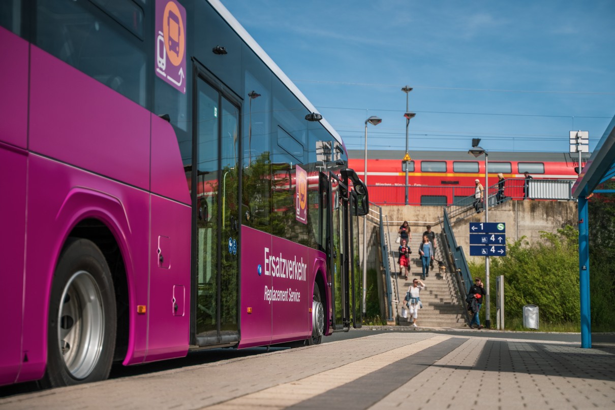 Ein Bus des Neuen Ersatzverkehrs wartet auf Reisende, die gerade aus dem Zug steigen