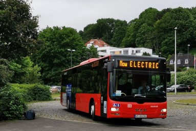 A converted red MAN diesel bus of the DB Regio subsidiary Autokraft in action. The sign reads ’Now Electric’