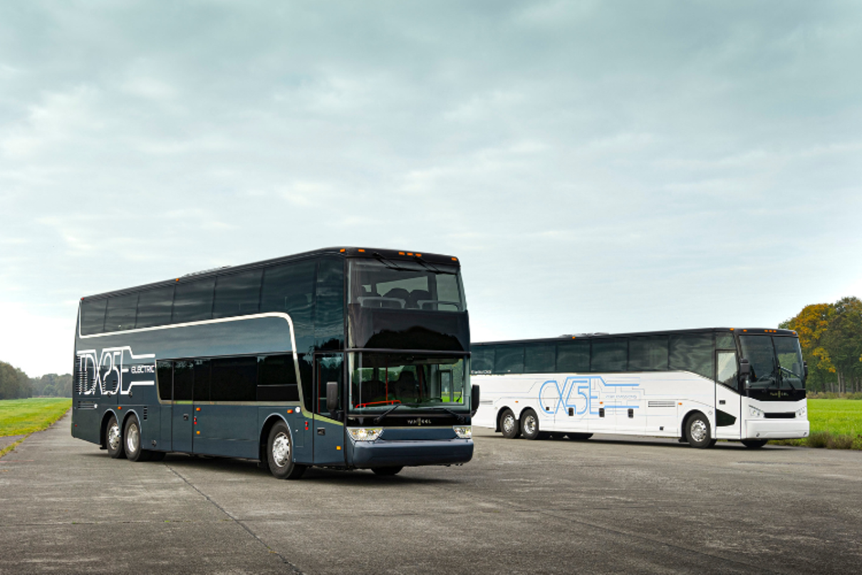 Zwei E-Reisebusse sind auf einer Betonfläche geparkt.