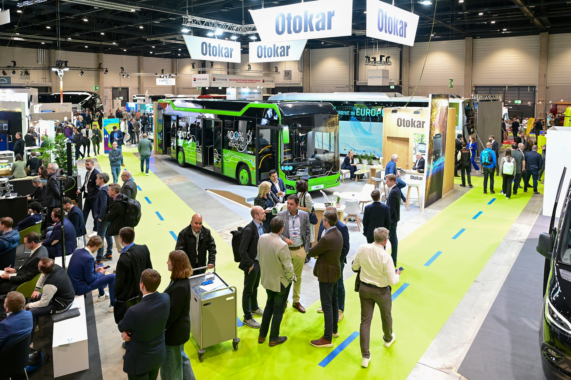 A display hall with various makes of buses along with trade visitors in conversation at BUS2BUS. 